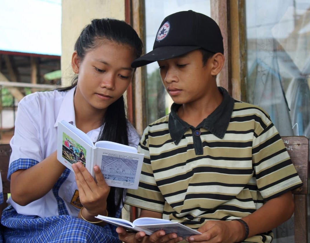Mentawai-students-sharing-language Indigenous Mentawai school student communicates with a young boy using the Mentawai language dictionary, published by @sukumentawai in 2019